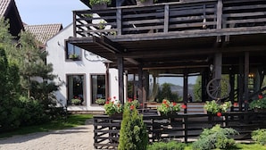 A two-story wooden building with a balcony, potted plants, and a stone pathway. - Casa Drumeţului (Savinesti)