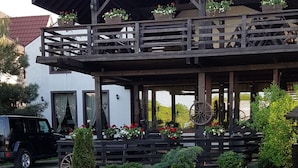 A rustic building with a wooden balcony, stone pathway, and potted plants. - Casa Drumeţului (Savinesti)