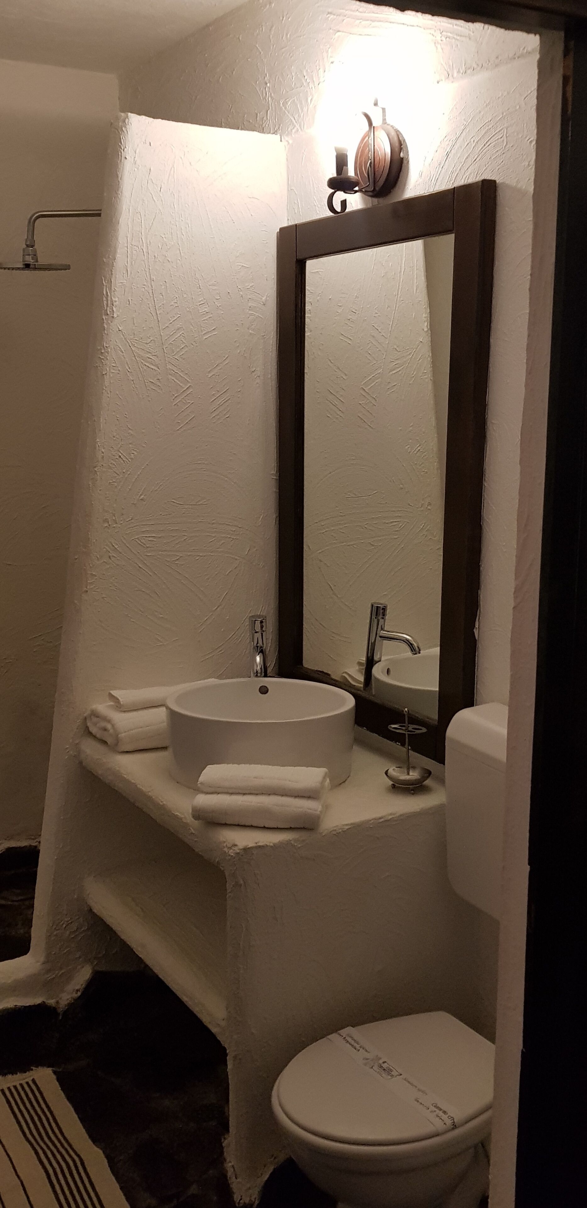 A bathroom with a white sink, a mirror, a toilet, and a towel rack.