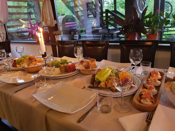 A dining table set with plates of food, glasses, and cutlery.