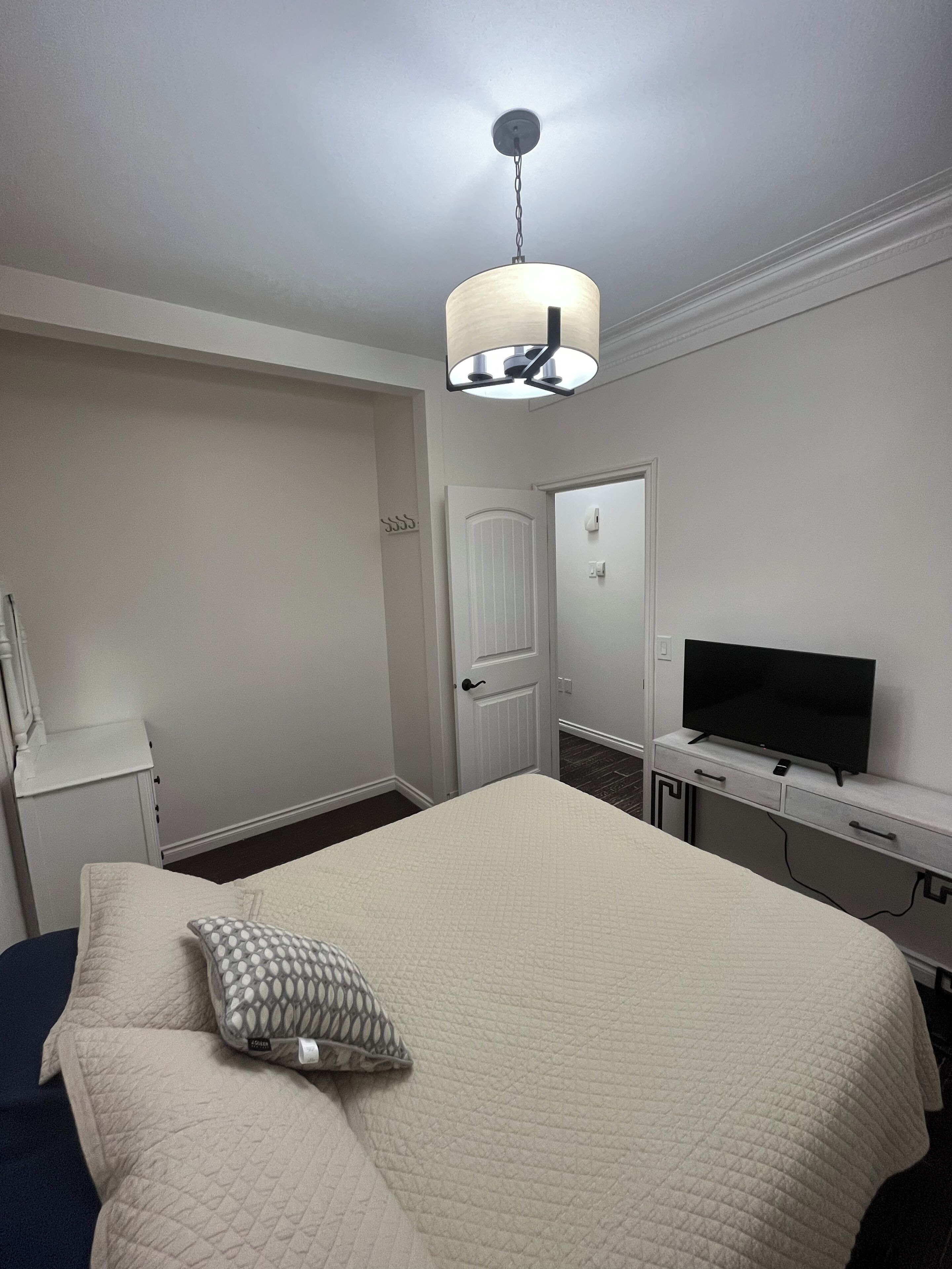 Hotellihuone, jossa on sänky, televisio, työpöytä ja ovi.
