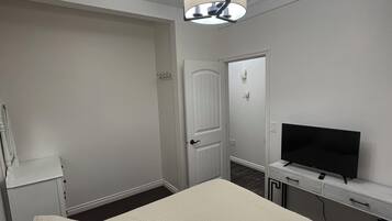 Hotellihuone, jossa on sänky, televisio, työpöytä ja ovi.