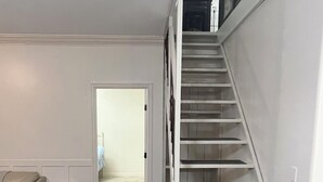 Trappe op til en etage, en hvid sofa og en dør til et andet rum.