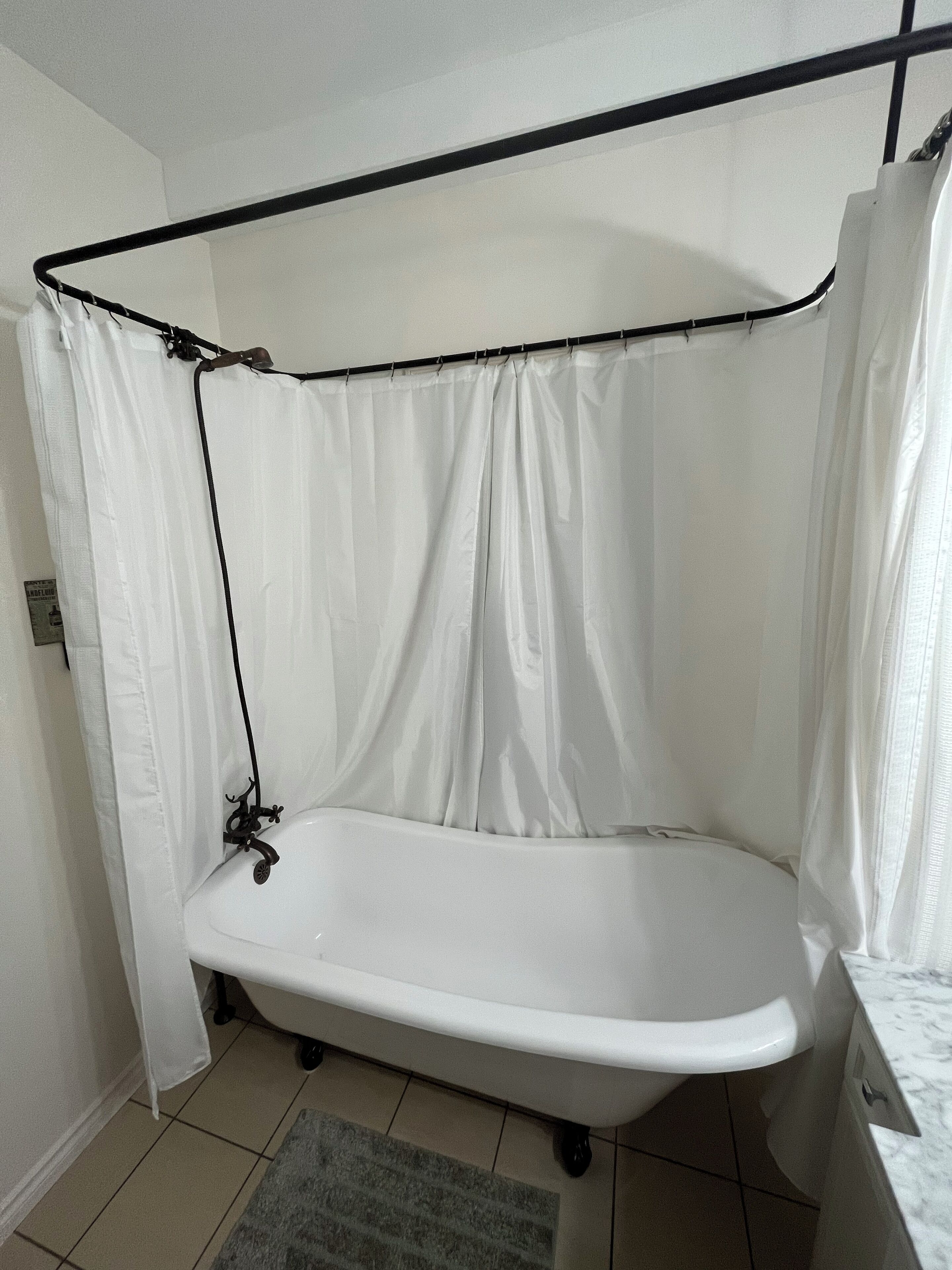 A bathroom with a bathtub, a shower curtain, and a tiled floor.
