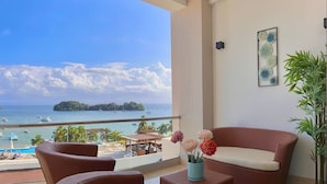 A balcony with a view of the sea, a sofa, a small table, and a potted plant. - Luxurious, Stunning Bay View Condo, King Bed, Spacious Terrace, Pool, Gym. (Samaná)