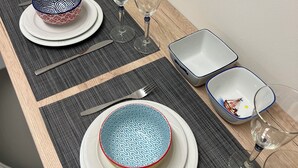 A dining table set with plates, bowls, glasses, and cutlery. - Stylish 1BR Apt. Opposite Metro- Balcony & Rooftop Lounge with Acropolis View (Athina)