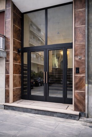 Entrada moderna de un edificio con puerta de vidrio y un pequeño escalón.