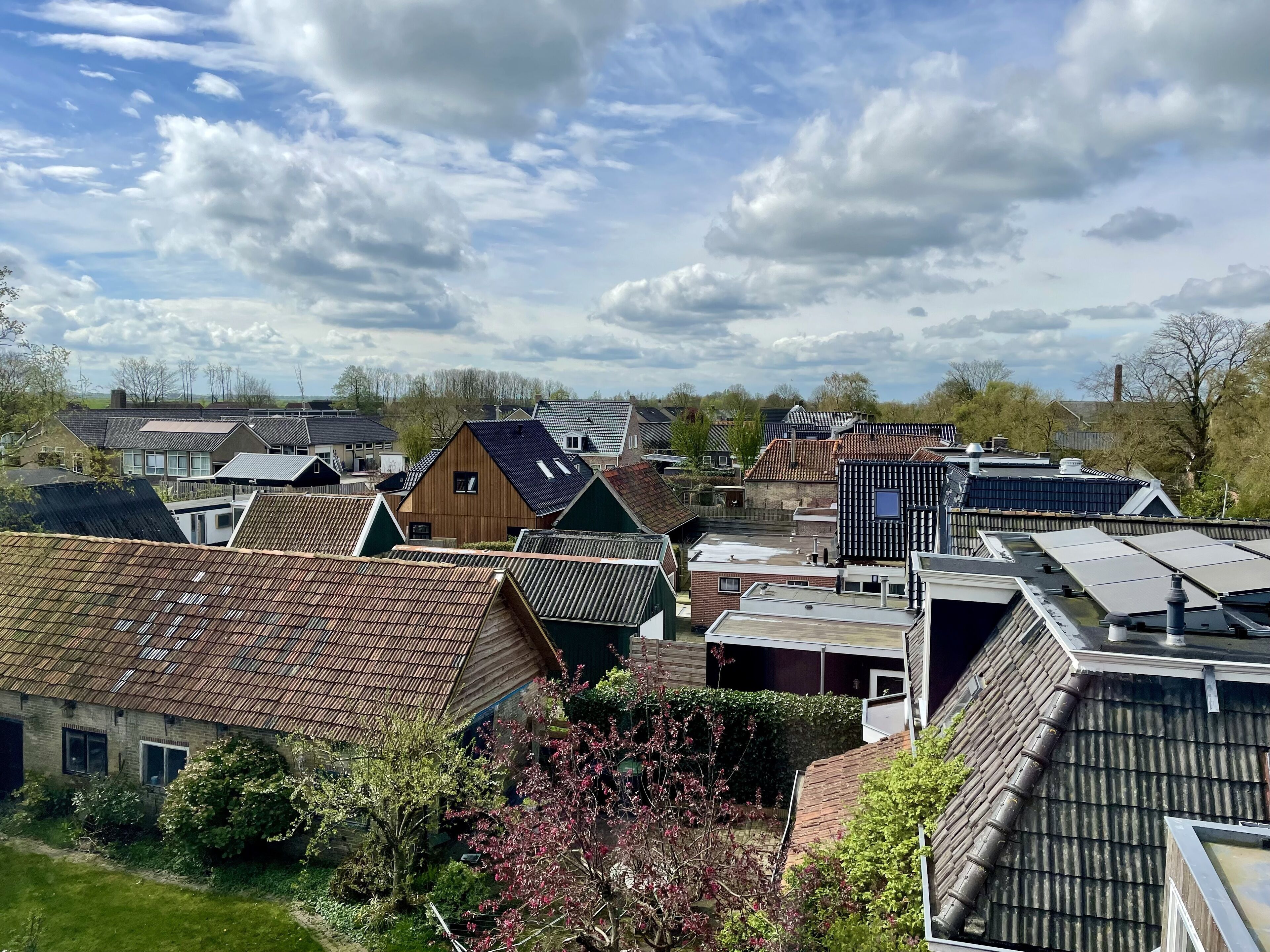 Ein Wohngebiet mit verschiedenen Häusern, einige mit Solaranlagen, und unterschiedlichen Dachformen.