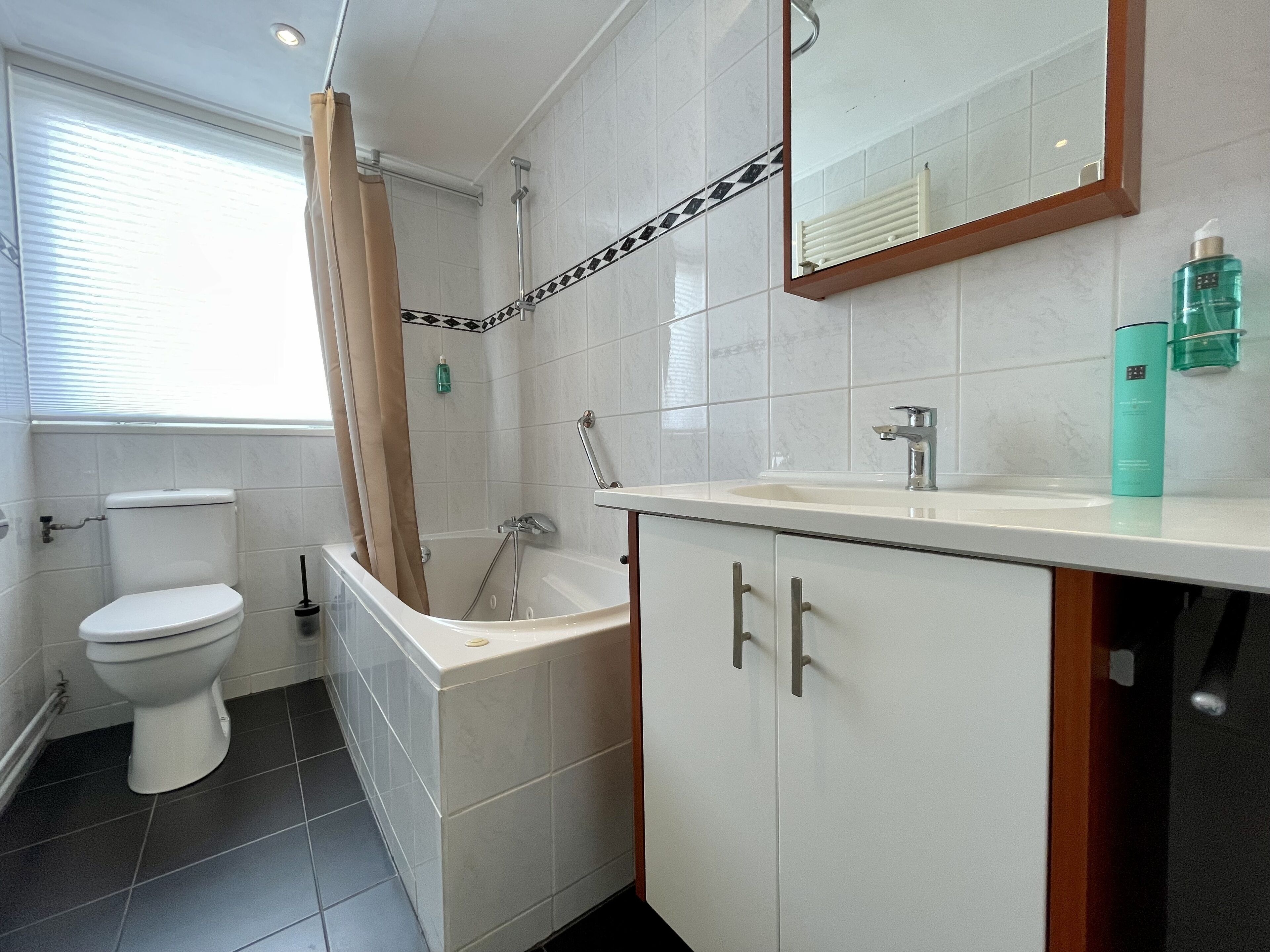 A modern bathroom with a toilet, bathtub, and sink.