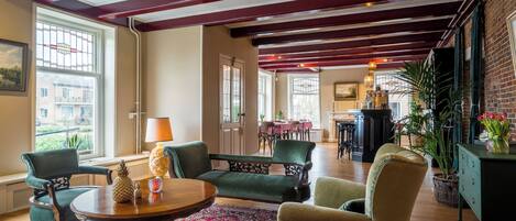 A spacious room with a high ceiling, wooden beams, a fireplace, and a dining area with a table and chairs.