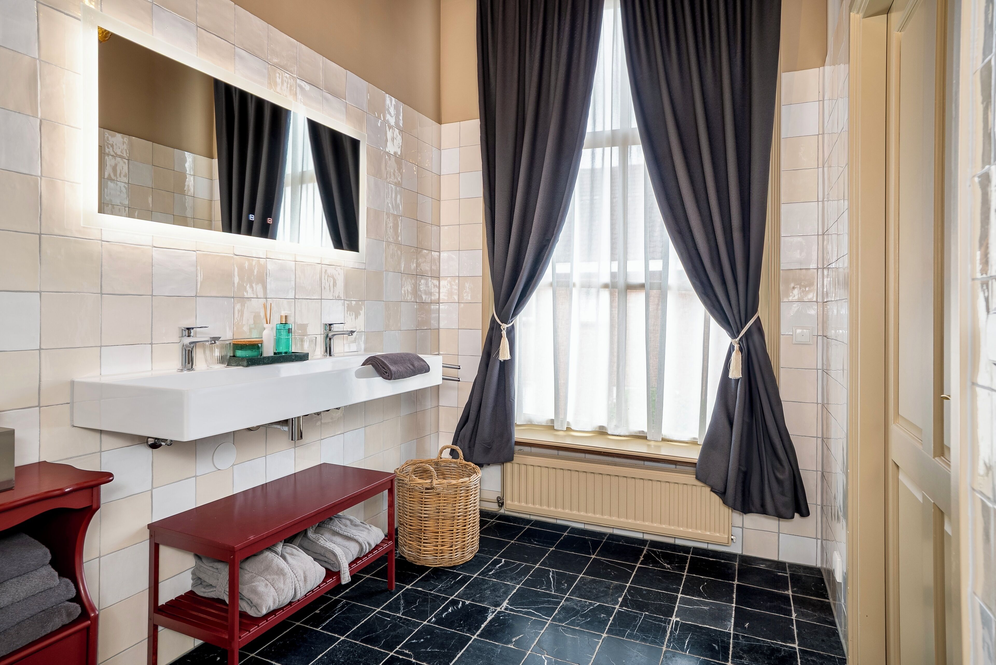A bathroom with a white sink, mirror, and black tiled floor.