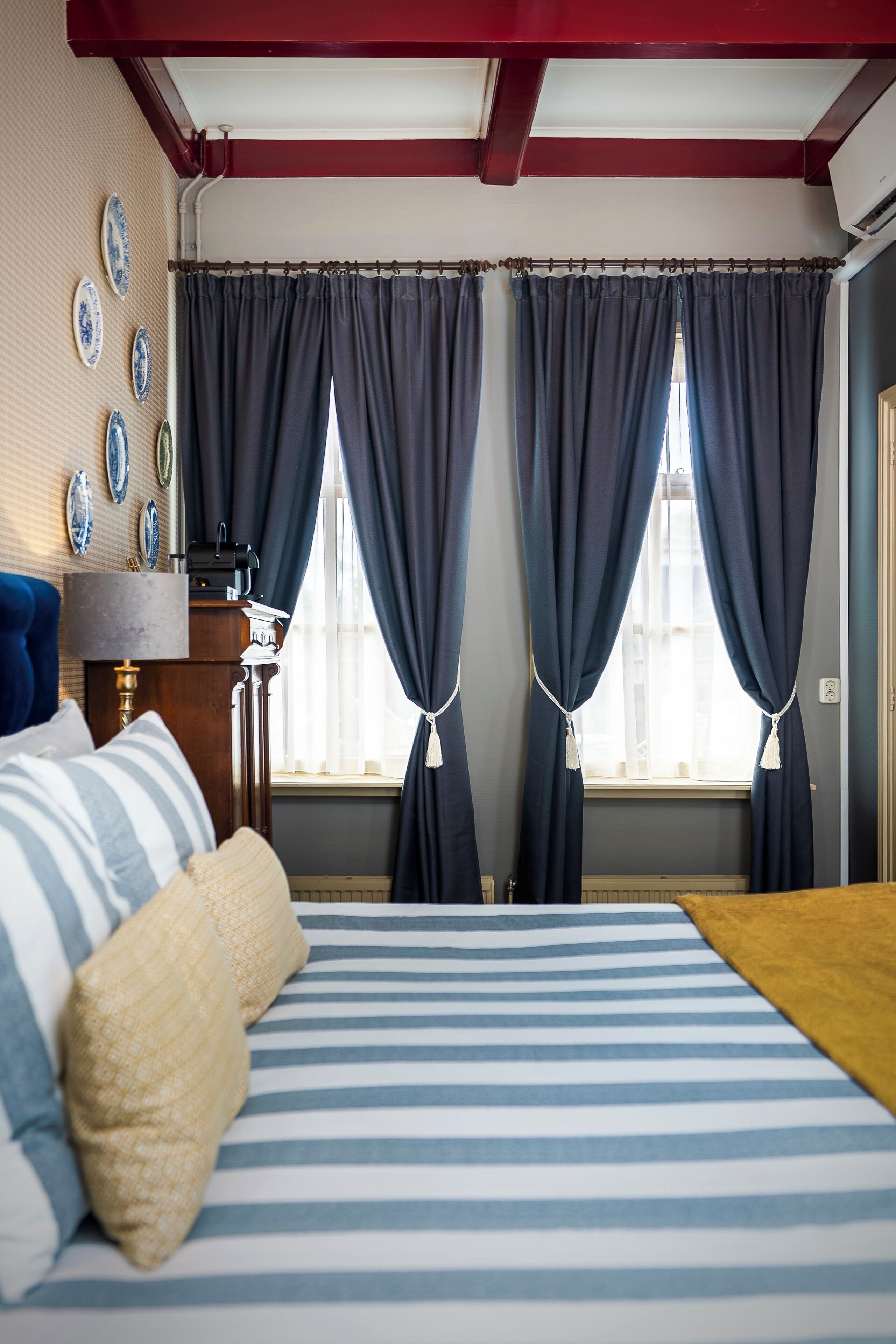 A bedroom with a bed, a nightstand, a lamp, and a window with curtains.