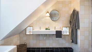 Een moderne badkamer met een wit wastafelmeubel, een ronde spiegel en een handdoekrek.