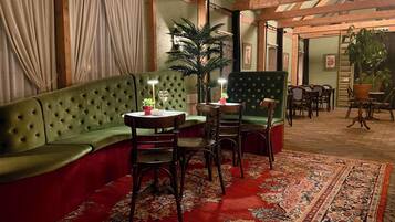 Una habitación acogedora con un sofá verde, una mesa de comedor con sillas y una planta grande en maceta.
