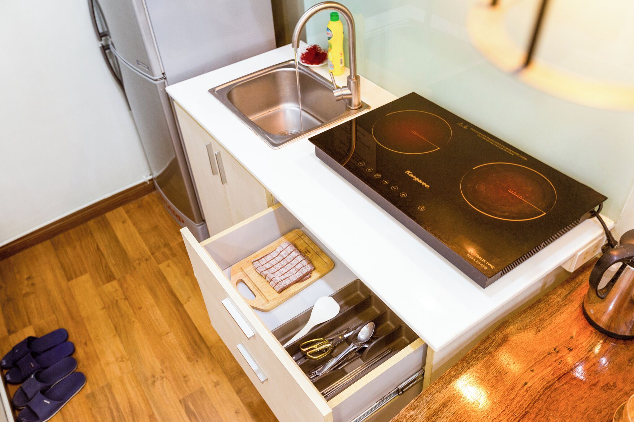 A compact kitchen with a built-in sink, a stovetop, and a drawer with utensils.