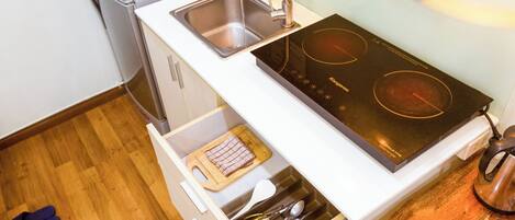 A compact kitchen with a built-in sink, a stovetop, and a drawer with utensils.