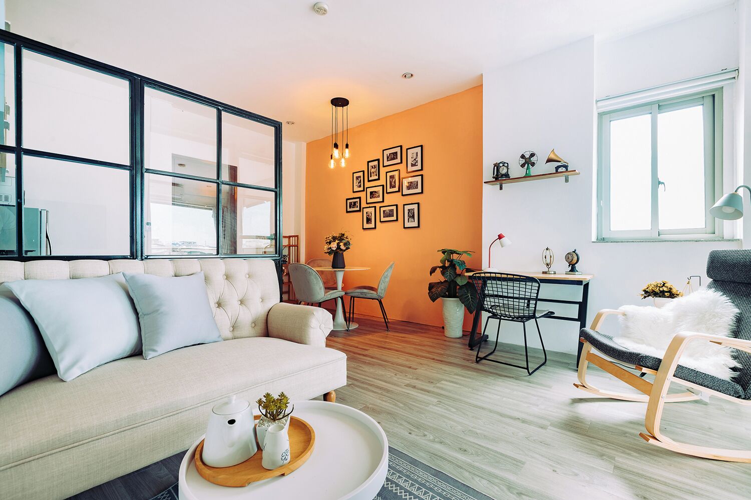 A modern living room with a sofa, chairs, a dining table, and a large window.