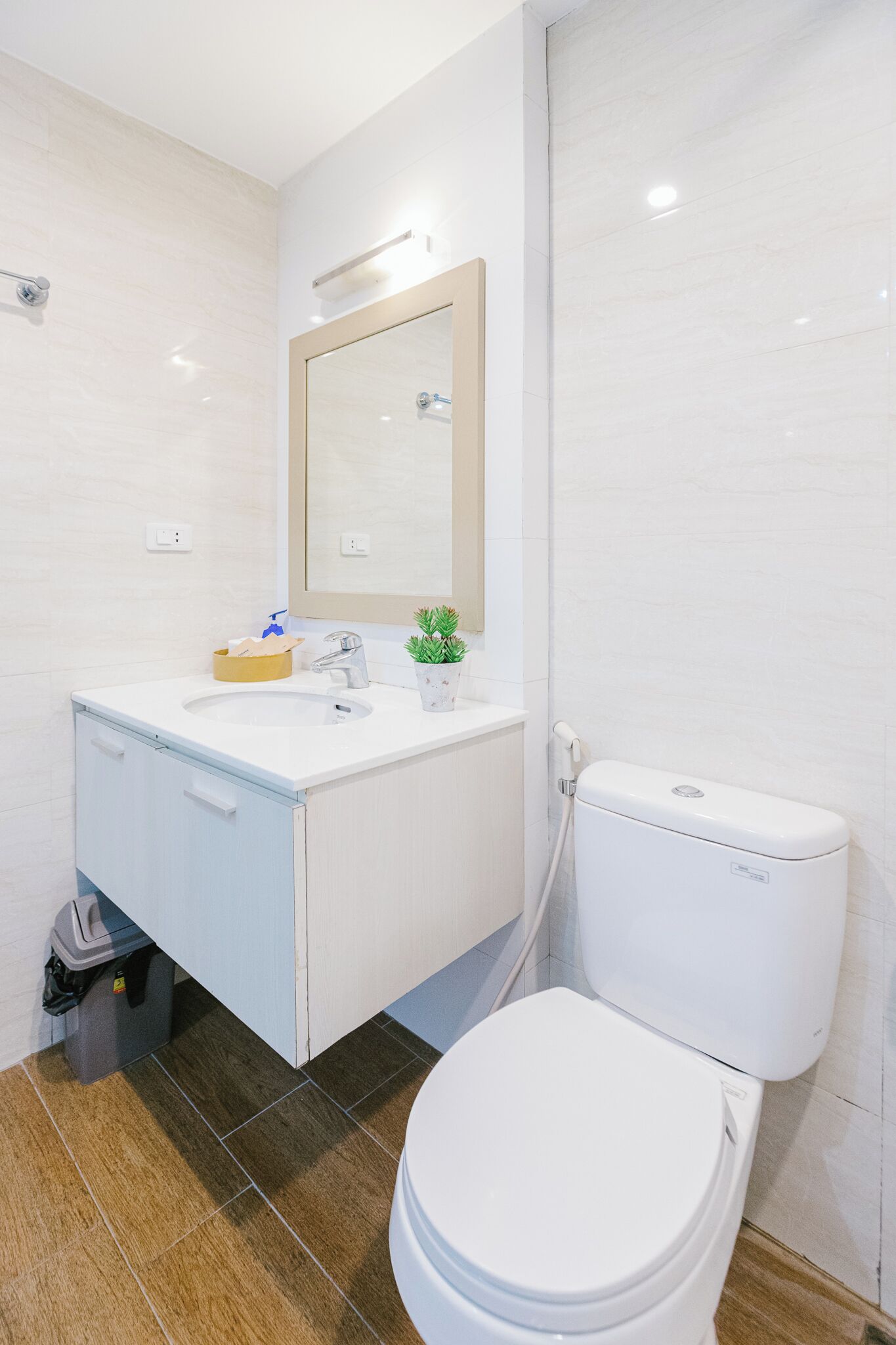 A modern bathroom with a white sink, mirror, and toilet.