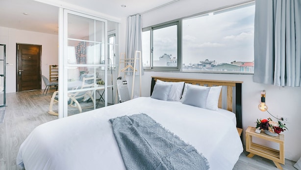 Une chambre d’hôtel moderne avec un grand lit, une vue sur la ville et un balcon équipé d’une chaise.
