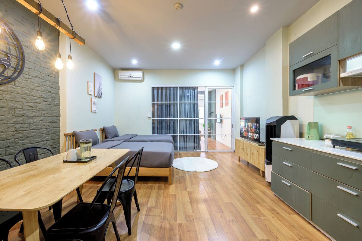A modern kitchen with wooden cabinets, a dining table with chairs, and a large window with curtains.
