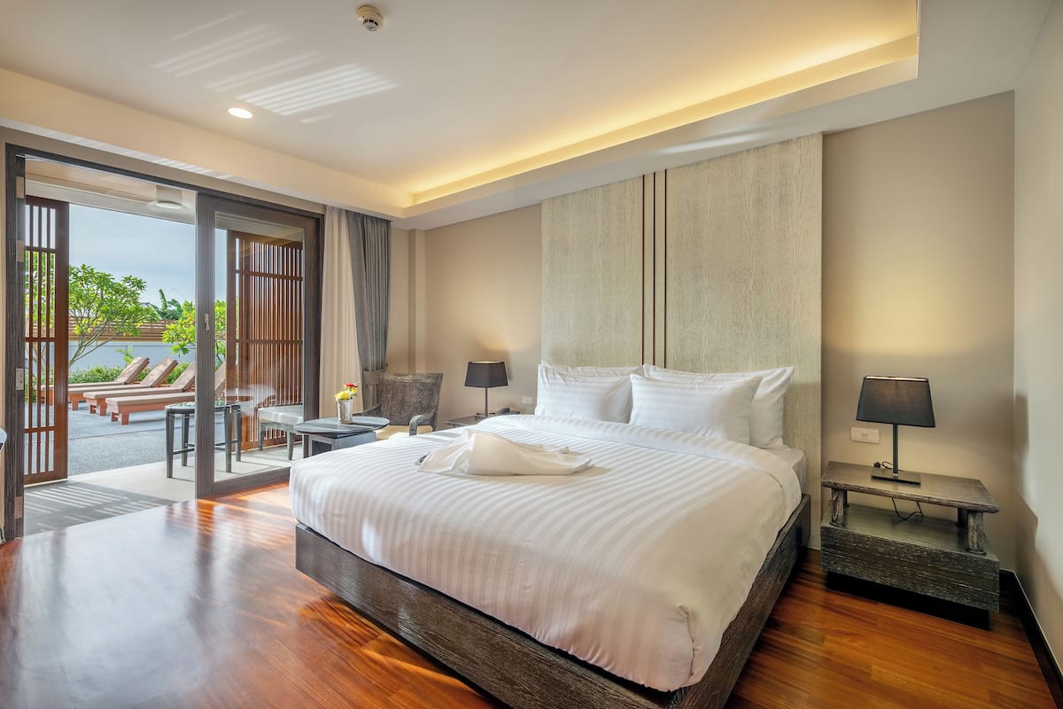 A hotel room with a large bed, a desk, a chair, and a view of the outdoors.