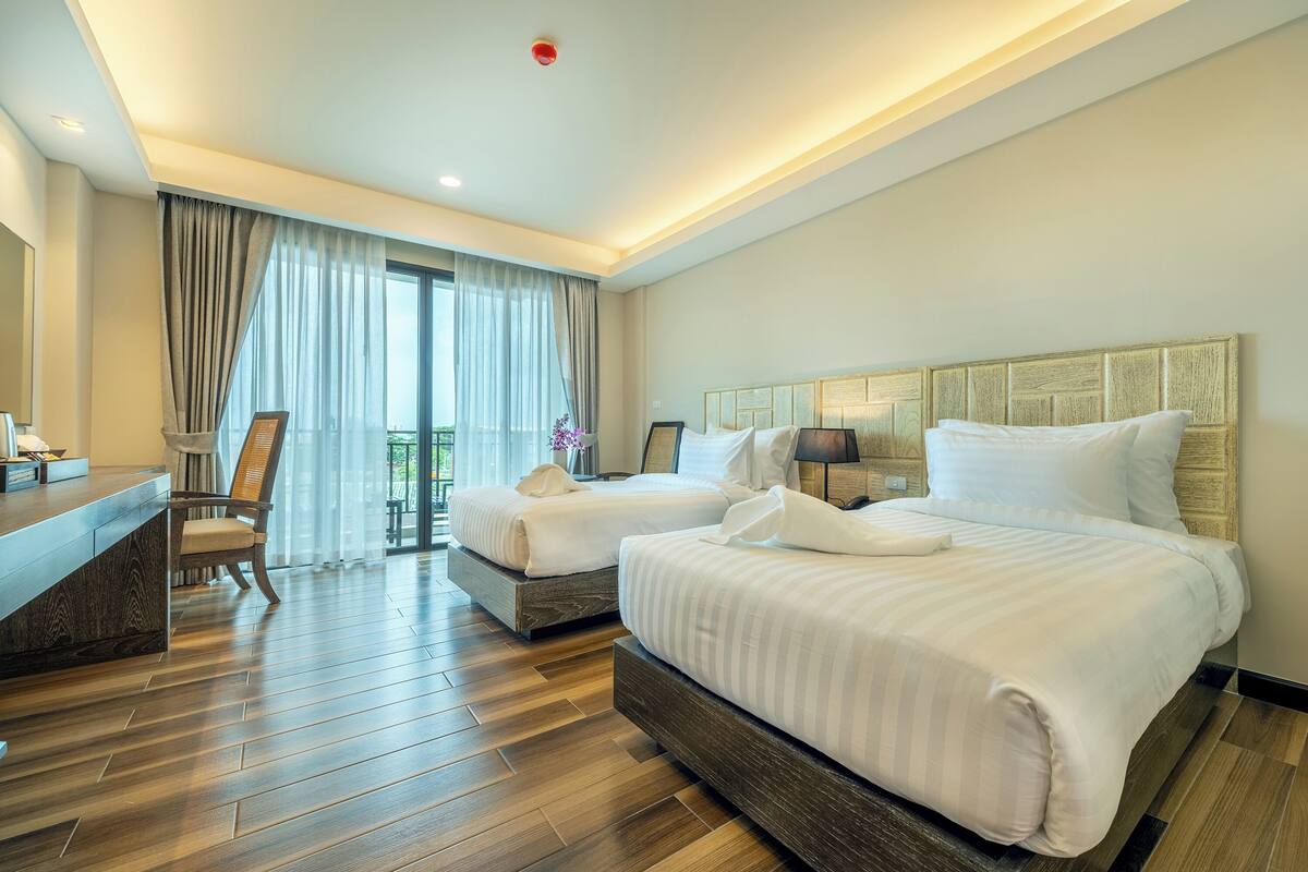 A hotel room with two beds, a desk, and a chair.