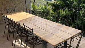 Et træbord og stole under et pergola med udsigt til et bjerg.