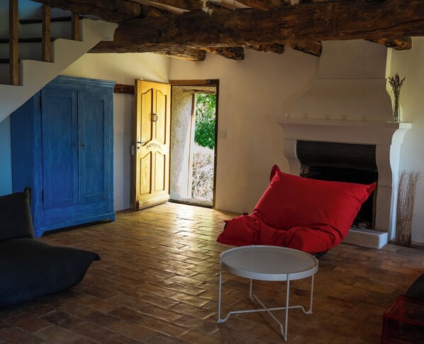 Une pièce avec un plancher en bois, une armoire bleue, une chaise rouge, une petite table et une cheminée.