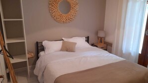 A bedroom with a bed, a bedside table with a lamp, a shelf unit, and a circular wall decoration. - Maison de Montagne Avec Jardin Privé (Sarrancolin)