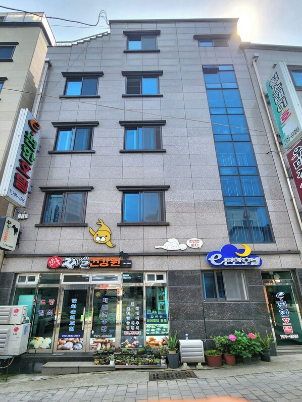 A multi-story building with various storefronts, including a visible restaurant and a shop with a cartoon character sign. - e cozy Hotel (Ulleung)