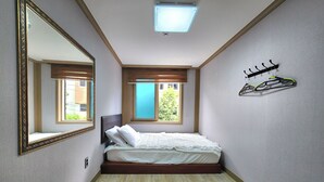 Un dormitorio con cama, un espejo grande, una ventana y una lámpara en el techo.