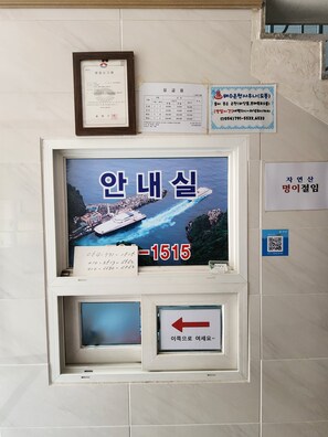 A framed certificate, a digital display with a ship image and text, and a directional sign. - e cozy Hotel (Ulleung)