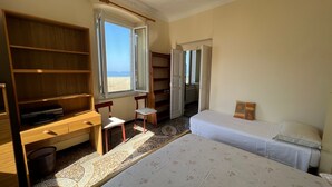 A room with a bed, a desk, and a chair. There is a window with a view of the beach. - Vast panoramic apartment 3 minutes from the sea (Camogli)