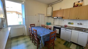 A compact kitchen with a dining table, chairs, a stove, a washing machine, and a sink. - Vast panoramic apartment 3 minutes from the sea (Camogli)