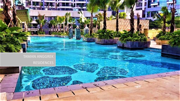 A swimming pool with clear blue water, surrounded by planters with greenery and a modern building in the background.