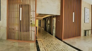 A hallway with a patterned floor, wooden panel dividers, and a bench.