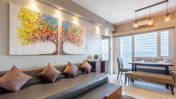 Un salon moderne comprenant un canapé, une table à manger et deux grandes peintures abstraites.