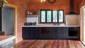 A modern kitchen with wooden walls, a black countertop, and a built-in oven.