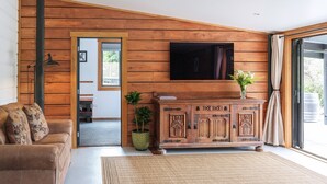 A living room with a wooden wall, a sofa, a TV, and a cabinet.