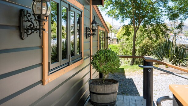 A wooden deck with a potted tree, a bench, and a railing.