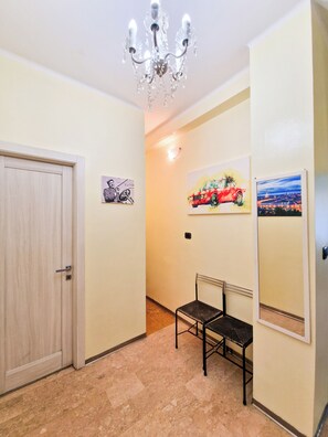 A hallway with a wooden door, a black chair, and three wall-mounted pictures.