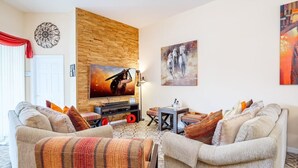 Un salon avec deux canapés, une table basse, un téléviseur et des œuvres d’art accrochées aux murs.