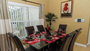 Une table à manger dressée pour quatre personnes, avec des nappes rouges et des chaises noires.