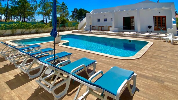A pool area with lounge chairs and a building with a white facade.