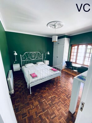 Ein Zimmer mit Bett, Schrank, Heizkörper, Schreibtisch und Stuhl.