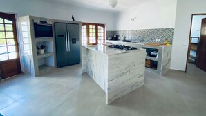 A modern kitchen with a marble island, stainless steel appliances, and a tiled backsplash.