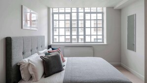 A bedroom with a bed, a window, a radiator, and a wall-mounted picture. - Clerkenwell 2-Bed · 2 Baths · Sleeps 6 (London)