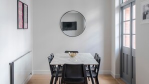 A dining area with a marble table, black chairs, a round mirror, and framed pictures on the walls. - Clerkenwell 2-Bed · 2 Baths · Sleeps 6 (London)
