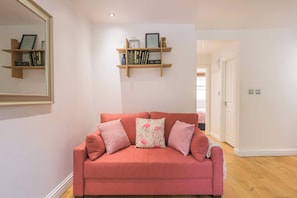 Relax in this stylish living room with a comfortable sofa, wooden shelf, and large mirror.