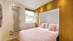 Un dormitorio con cama, armario de madera y ventana con cortinas.